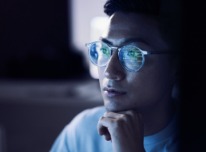 The reflection of a computer screen on a person's eyewear.