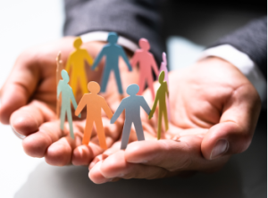 A hand holding a paper cutout of small figures holding hands.