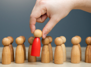 A hand picking out a singular red game piece from a line of many.