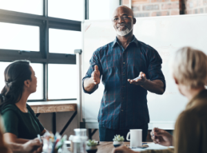 A man talking to his colleagues in a boardroom.