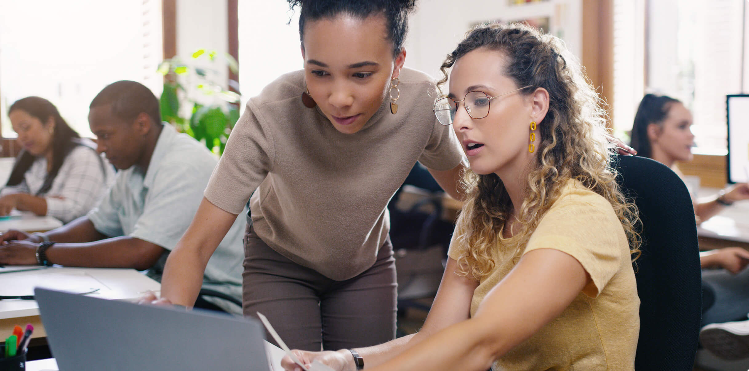 Two coworkers discussing something at a laptop screen.