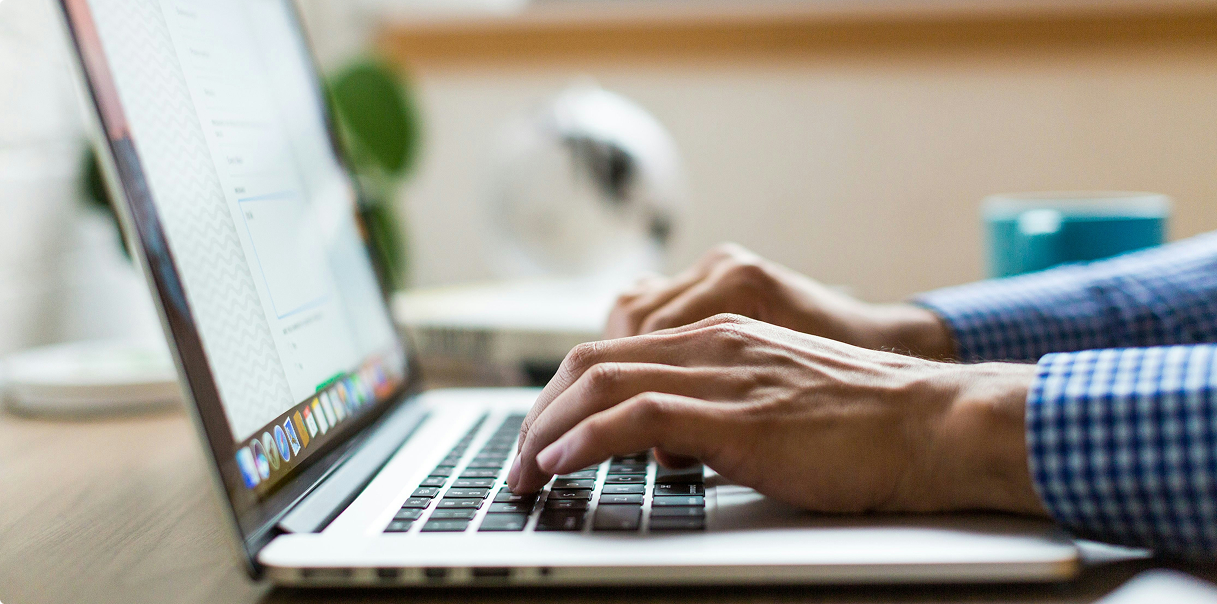A close-up of hands typing at a laptop.