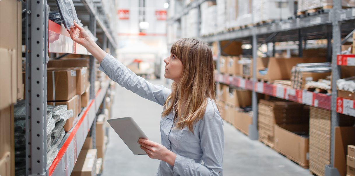 A woman looking at items on shelving in a warehouse setting.