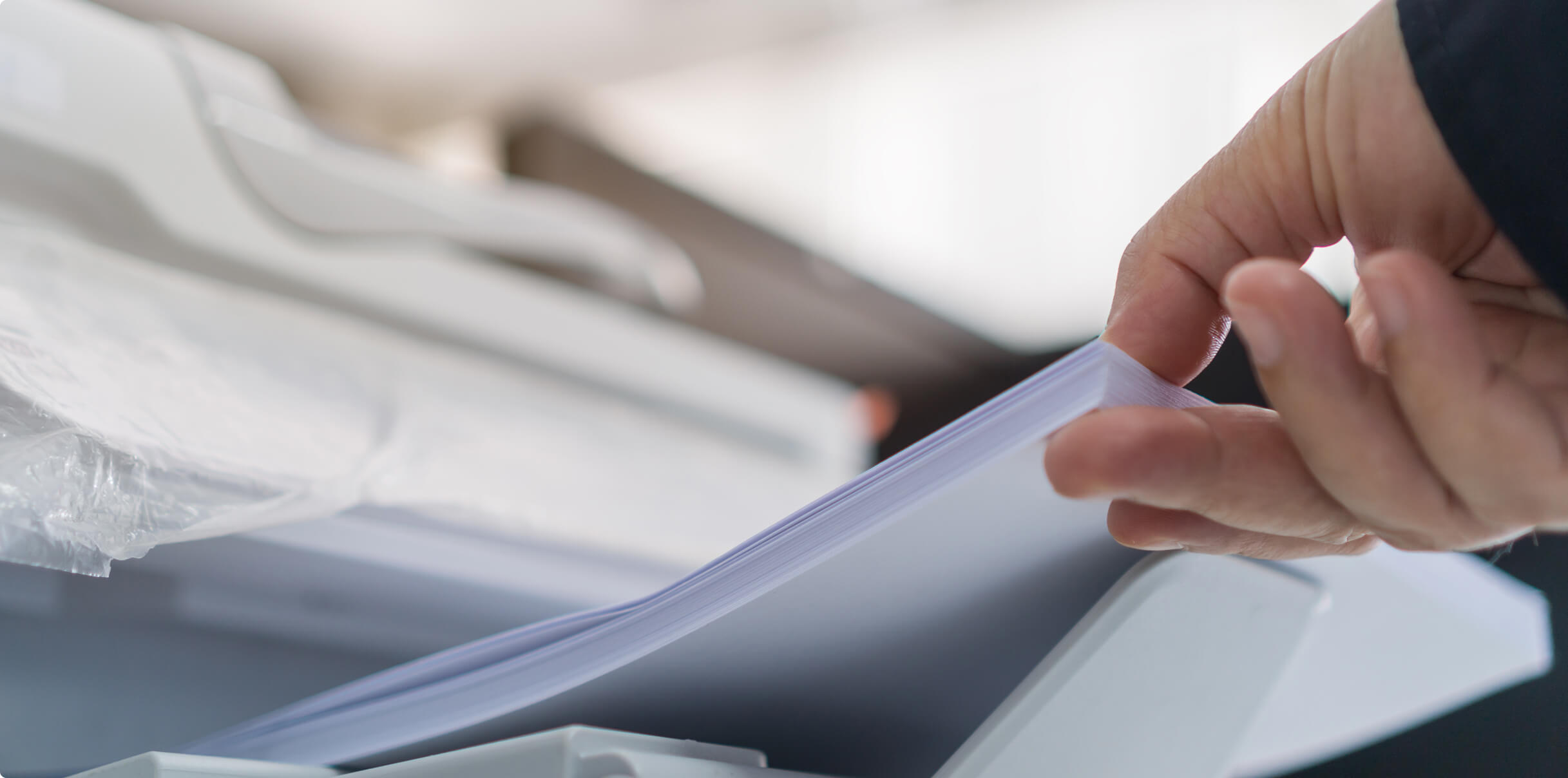 A close up of a hand holding a stack of printing paper.