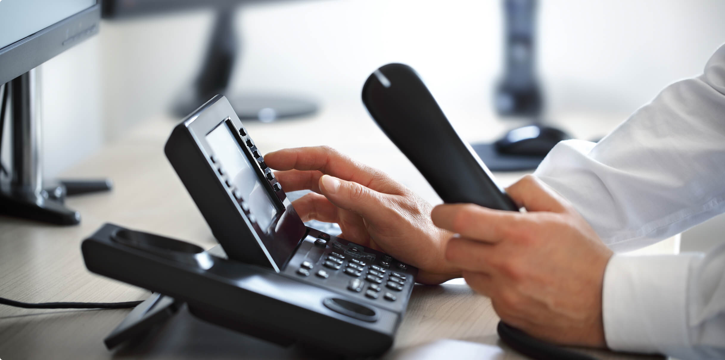 A close up of a person dialling on a landline phone.
