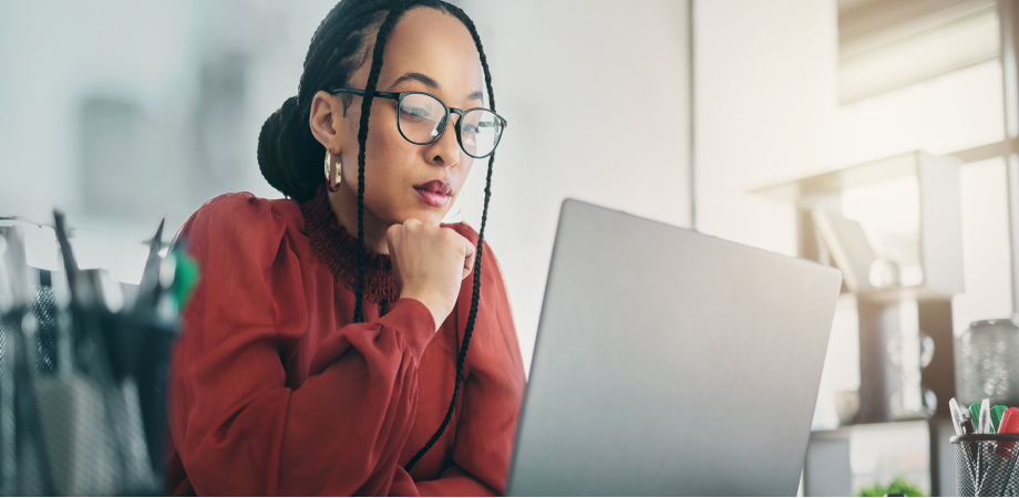A person sitting at their laptop looking deep in thought.
