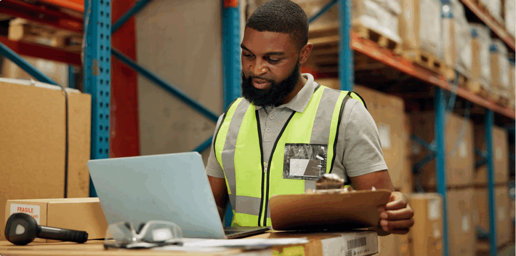A man working on a laptop in a warehouse.