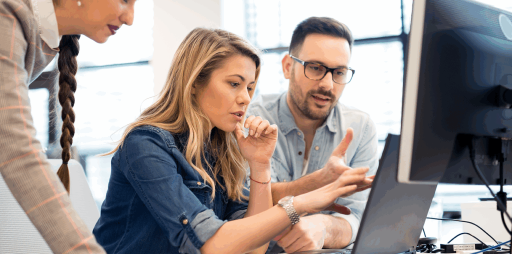 Three coworkers in discussion at a computer screen.