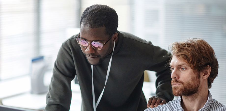 Two coworkers looking at a computer screen in deep thought.