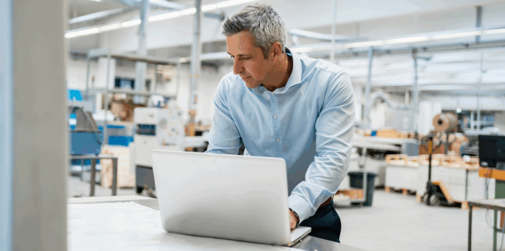 Man working on a laptop in a product shipment facility.