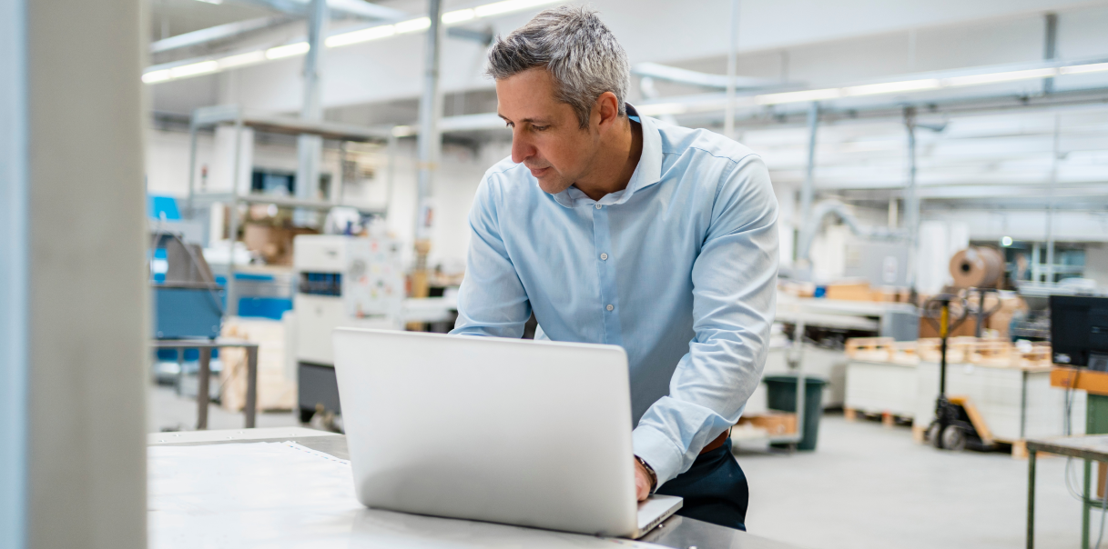 Man working on a laptop in a product shipment facility.