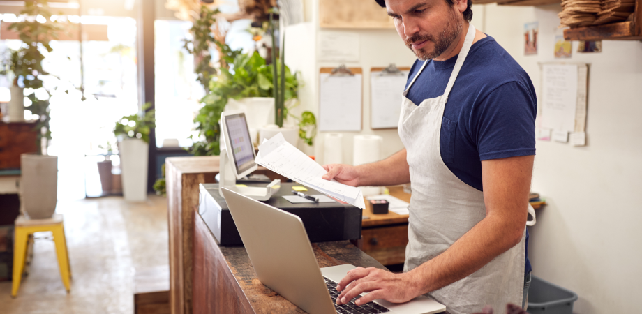 A person working in a retail setting, looking at a laptop screen.