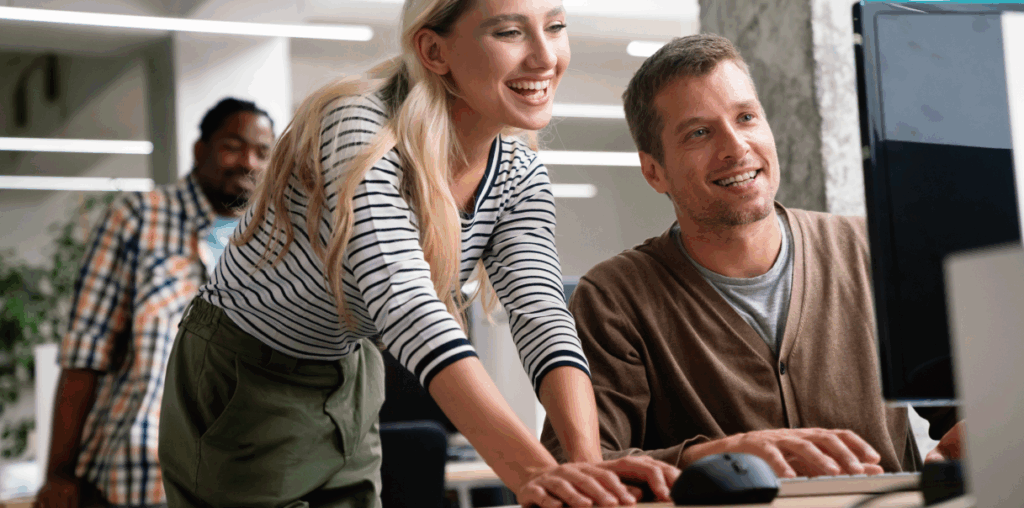 Coworkers sitting and standing while looking at a computer screen.