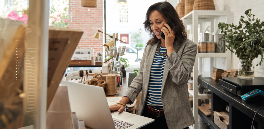 A small business owner on a phonecall and using their laptop.