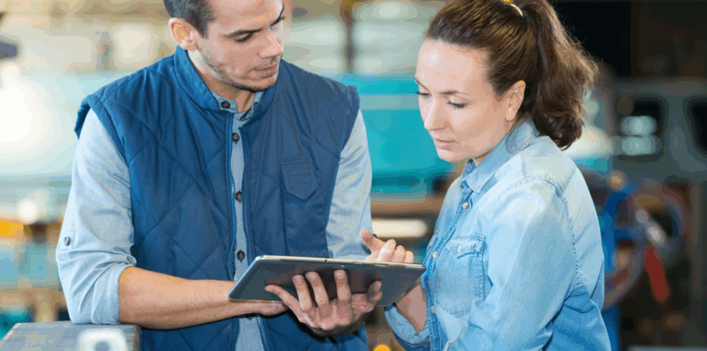 Two coworkers discussing something while holding an iPad.