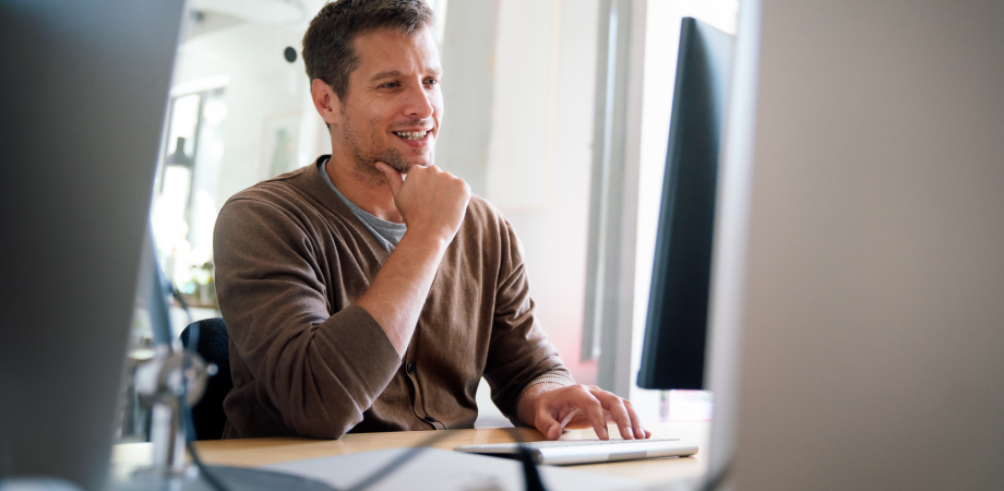 A man smiling while typing at a computer.