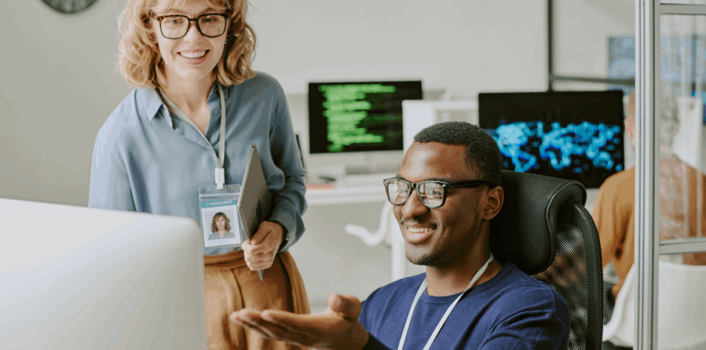 Two coworkers looking at a computer screen and smiling.