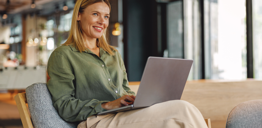 A woman sitting down on a chair and typing on a laptop.