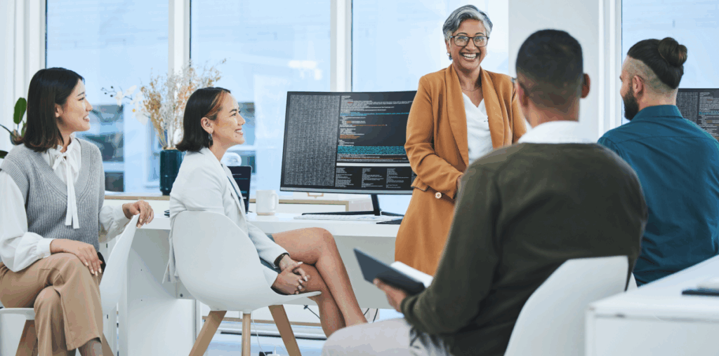 A woman standing in front of a group of coworkers in an office environment.