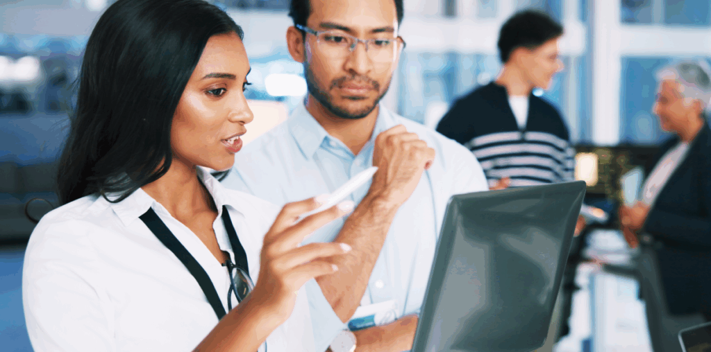 Two coworkers in discussion at a computer screen.