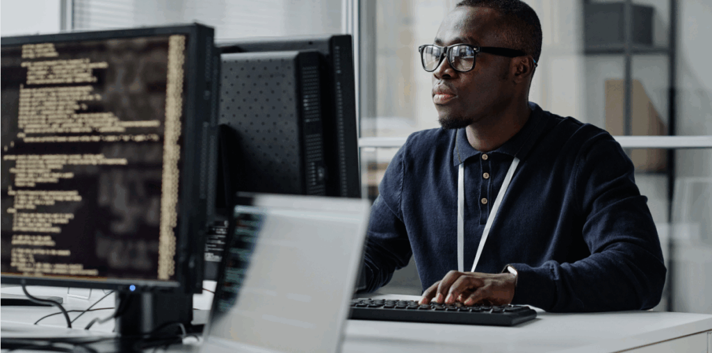 A man sitting at a desktop monitor and looking at the screen.