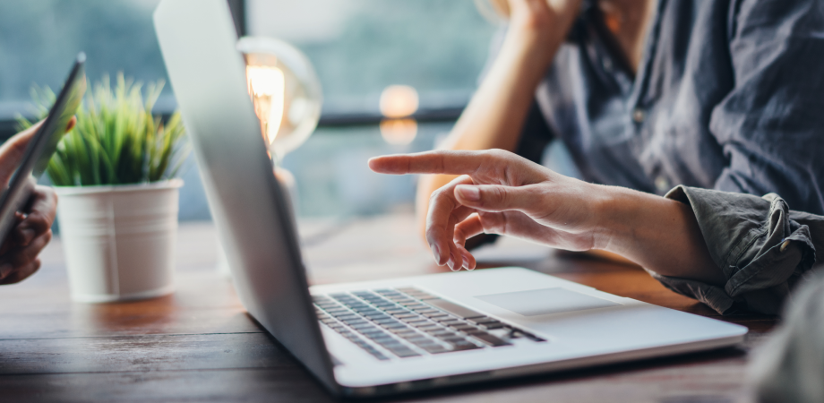Hand pointing to a laptop screen.